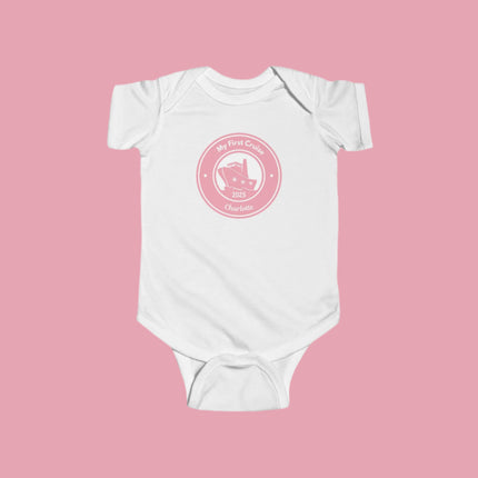 White baby onesie with pink graphic and text on a white background