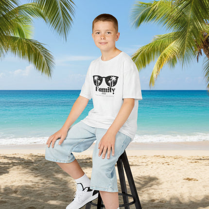 Boy sitting on a stool wearing a light blue t-shirt with sunglasses and personalized family vacation text